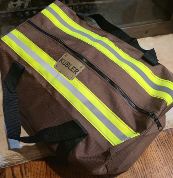Brown duffel bag with reflective stripes and 'name' brand logo on a wooden surface.