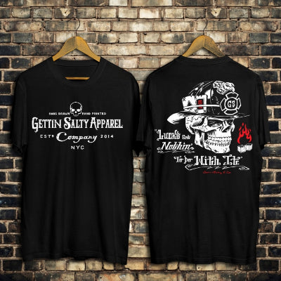 Two black t-shirts with text and graphics on hangers against a brick wall.
