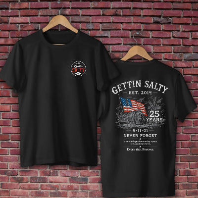 Two black short-sleeve t-shirts on wooden hangers against a red brick wall. The front shirt has a small circular 'Gettin' Salty' logo on the left chest, and the back shirt features a large white graphic with 'GETIN SALTY EST.