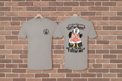 Two gray t-shirts with a cartoon character graphic and text on a brick wall background