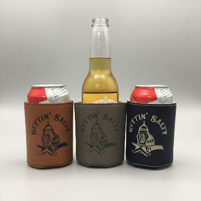 Three koozies in 'Gettin' Salty' branded can coolers on a wooden surface.