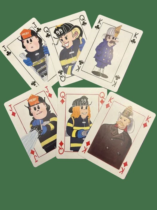 Five illustrated playing cards arranged on a solid green background. The cards feature cartoon firefighters and a captain, with jack, queen, and king faces visible.