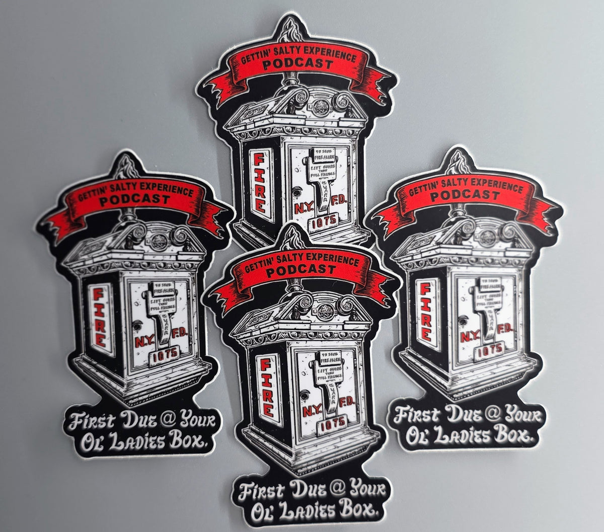 Four die-cut stickers featuring a vintage oil change counter illustration with red banners reading 'Sattin Salty Experience Podcast' and the phrase 'First Due @ Your Oil Lady Box' on a light gray background.