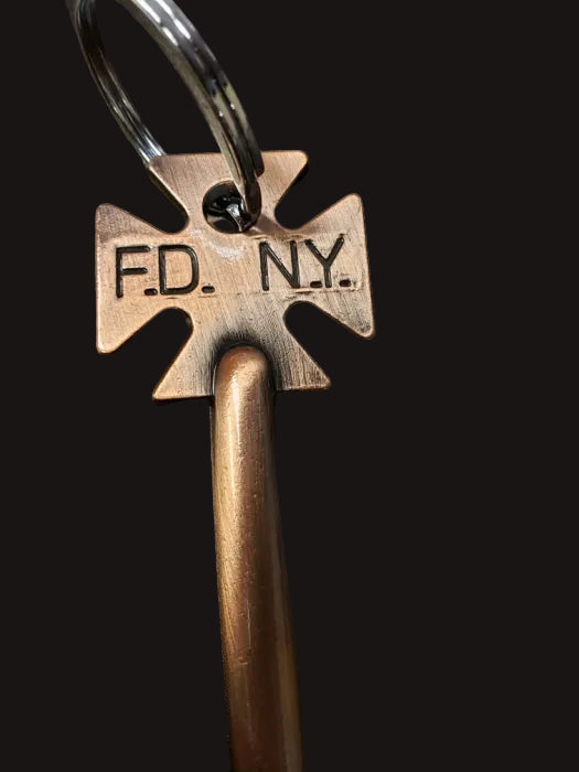 Bronze key with 'F.D. N.Y.' marking on a dark surface