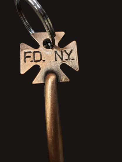 Bronze key with 'F.D. N.Y.' marking on a dark surface